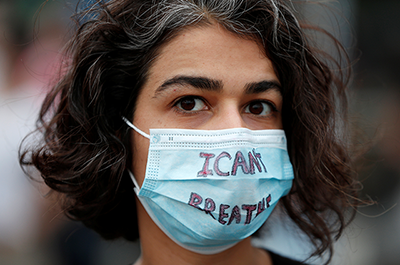 A protest wearing a face mask with the words "I can't breathe"