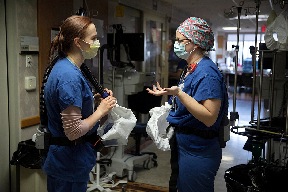 Nurse Kate Knepprath talks with nursing assistant Brittany Digman about a COVID-19 patient being treated at UW Health University Hospital in Madison, Wisconsin.