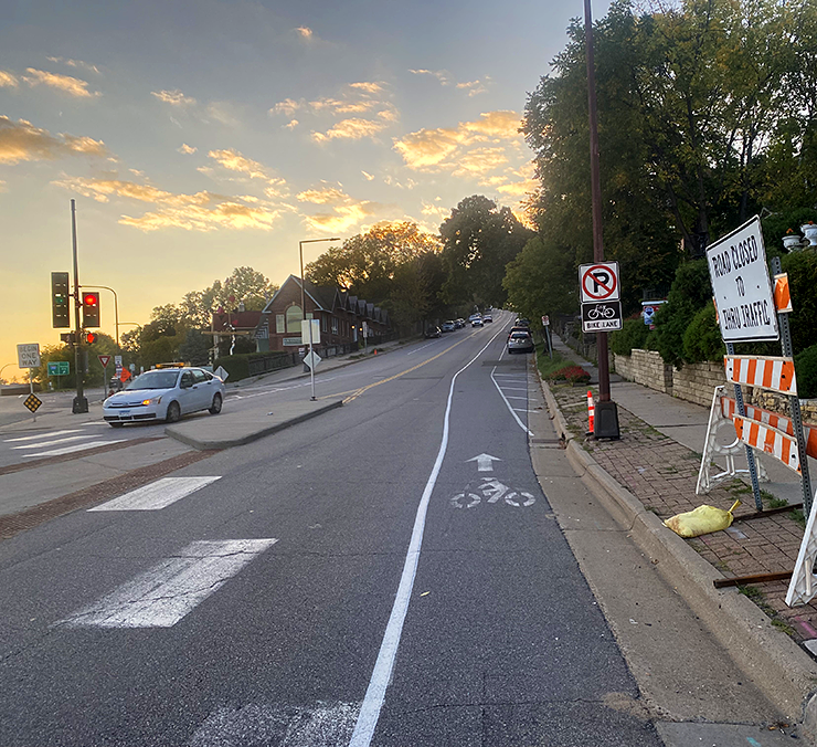 image of roadway shot at sunset with bike lane on right side of road centered in photo