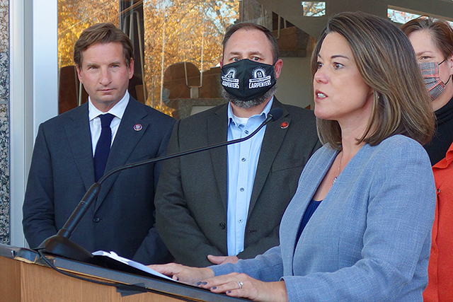 Rep. Angie Craig speaking on Tuesday about the infrastructure bill as Rep. Dean Phillips, business representative for the regional council of carpenters Ryan Pecinovsky, and Transportation Commissioner Margaret Anderson Kelliher look on.