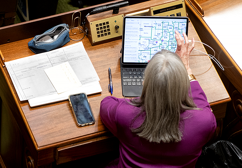 State Rep. Ginny Klevorn studying the new maps at her desk on the Minnesota House floor.