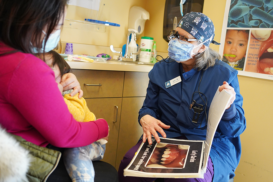 Hygienist Kate Iverson talking to a parent about oral health during a dental exam at Roselawn Clinic.