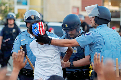 A protester is detained by police officers