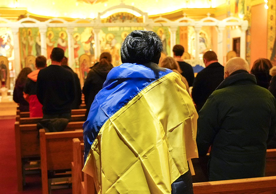 A woman wrapped in a Ukrainian flag at the Constantine Ukrainian Catholic Church for a service on Thursday, Feb. 24.