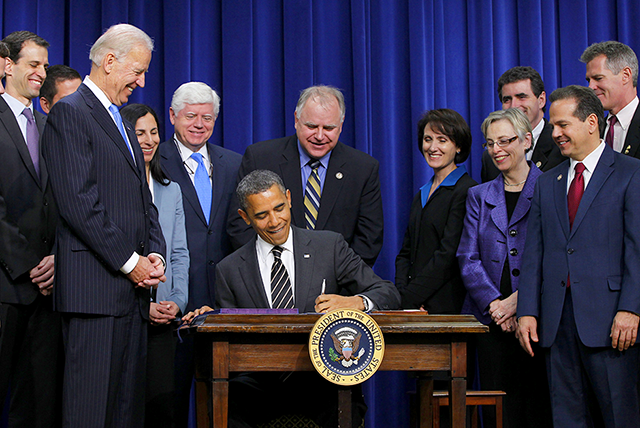 Then-President Barack Obama signing the STOCK Act in the Eisenhower Executive Office building on April 4, 2012. Standing behind Obama is then-Rep. Tim Walz.