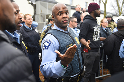 A police officer talks with demonstrators in front of the north Minneapolis police precinct