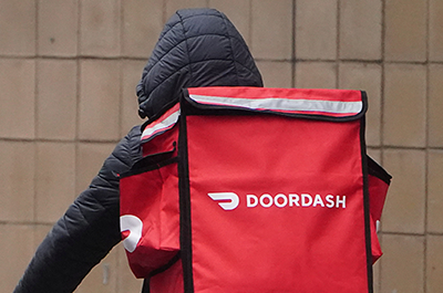 A delivery person for DoorDash riding his bike in the rain.