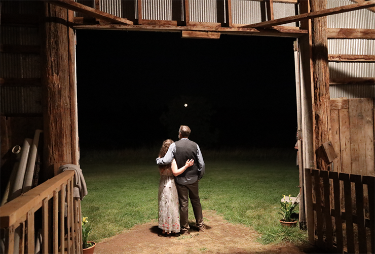 Heather Mary and John watch the moonrise on their wedding day from the large barn doors of their Barnum farm.