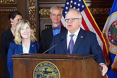Gov. Tim Walz shown speaking during a March 21 press conference outlining budget and tax targets as House Speaker Melissa Hortman, left, and Senate Majority Leader Bobby Joe Champion, right, et al., look on.
