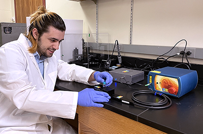 Hamline physics student Josh Sedarski pictured with a portable Raman Spectrometer.