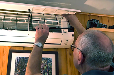 Michael Overend adjusts the indoor unit of his home's heat pump.