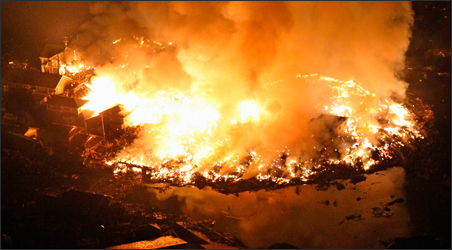 Houses burn at night following an earthquake in Natori City, Miyagi Prefecture, northeastern Japan