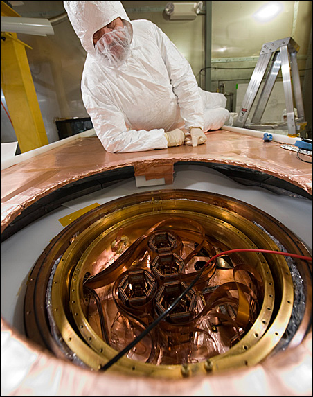 A scientist observes detectors set up to interact with particles from dark matter.