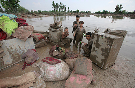 Boys sit with their belongings beside receding flood waters in Nowshera, located in Pakistan's northwest Khyber-Pakhtunkhwa Province on Monday.